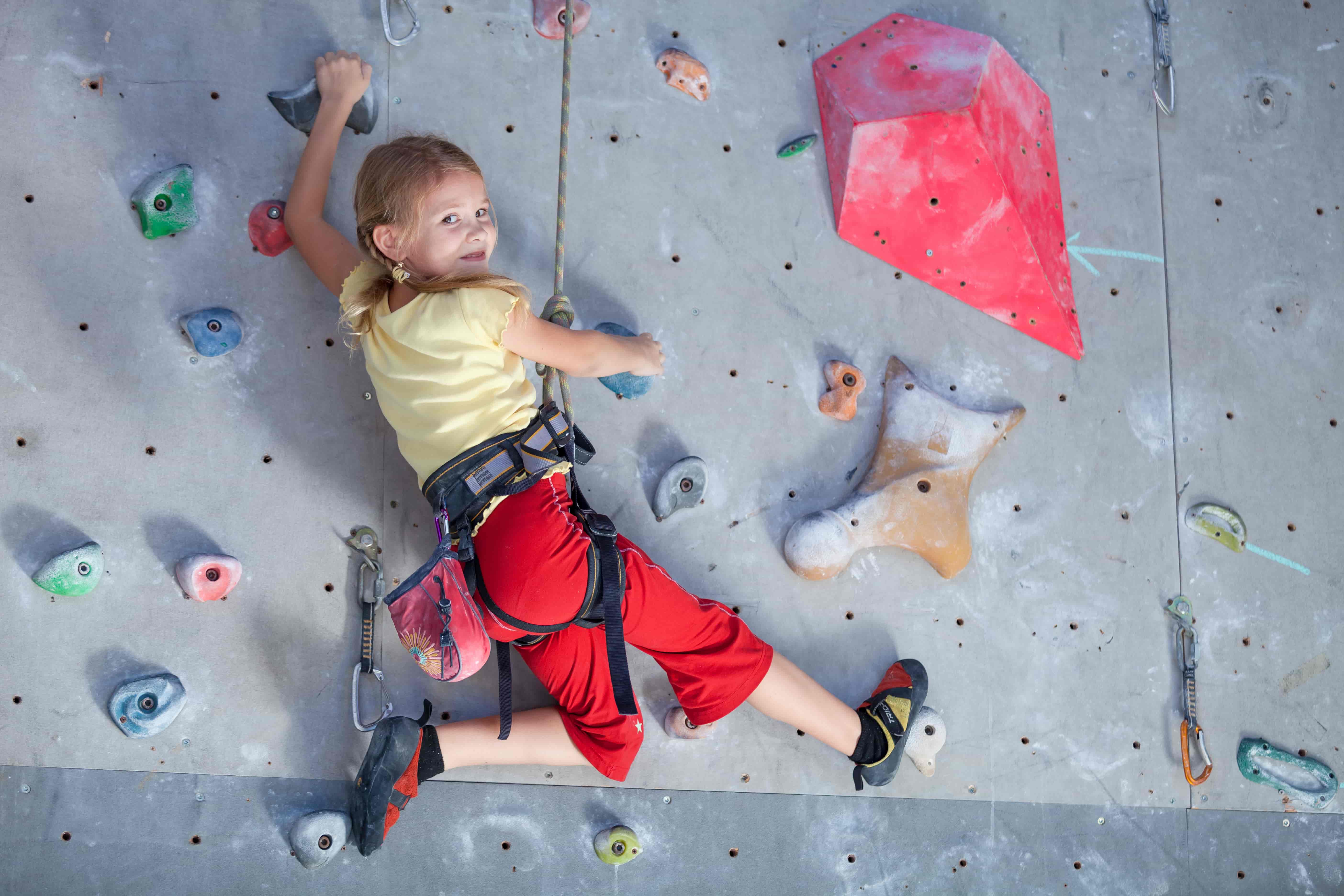 Niña escalando en un rocódromo