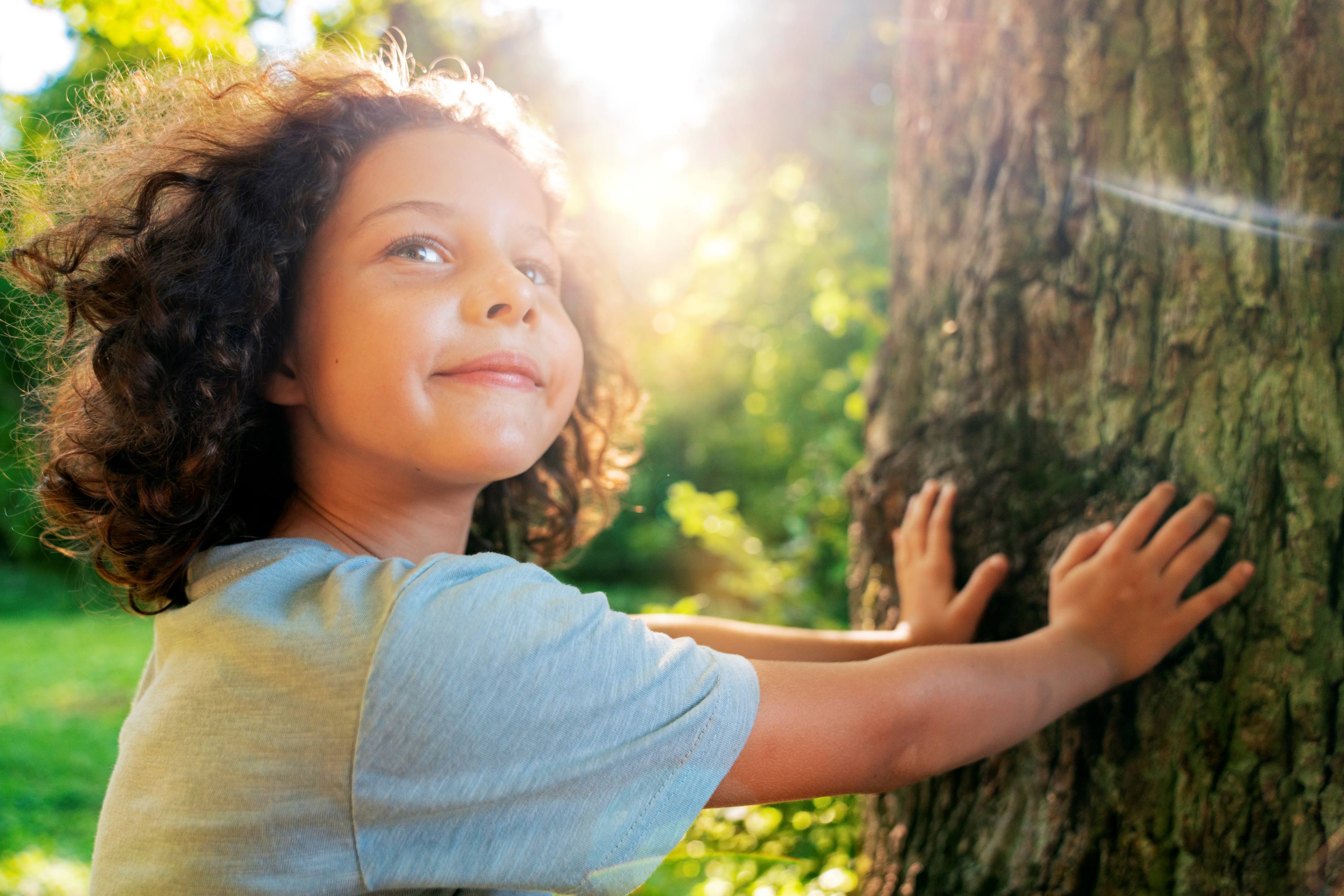 Niño sonriente tocando un arbol