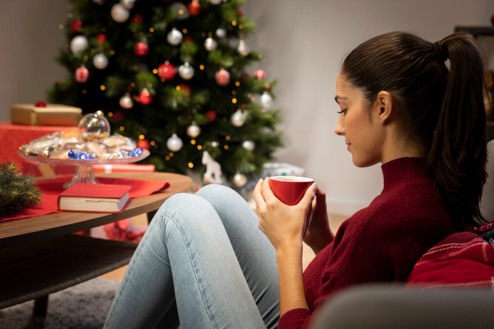 Mujer mirando una taza con fondo navideño. Freepik